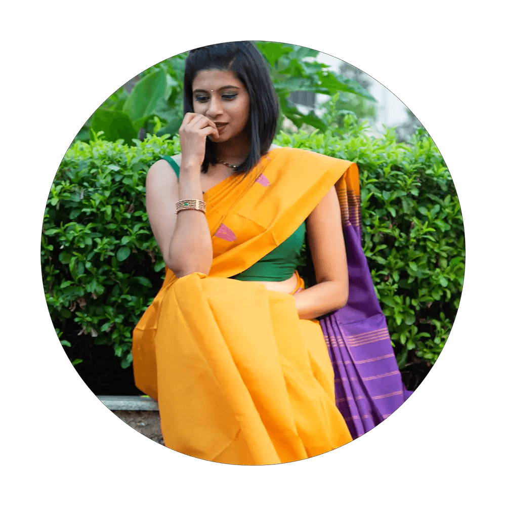 A female model sitting in a garden in a yellow cotton saree from Devotion to Beauty collection from Seven Sarees.